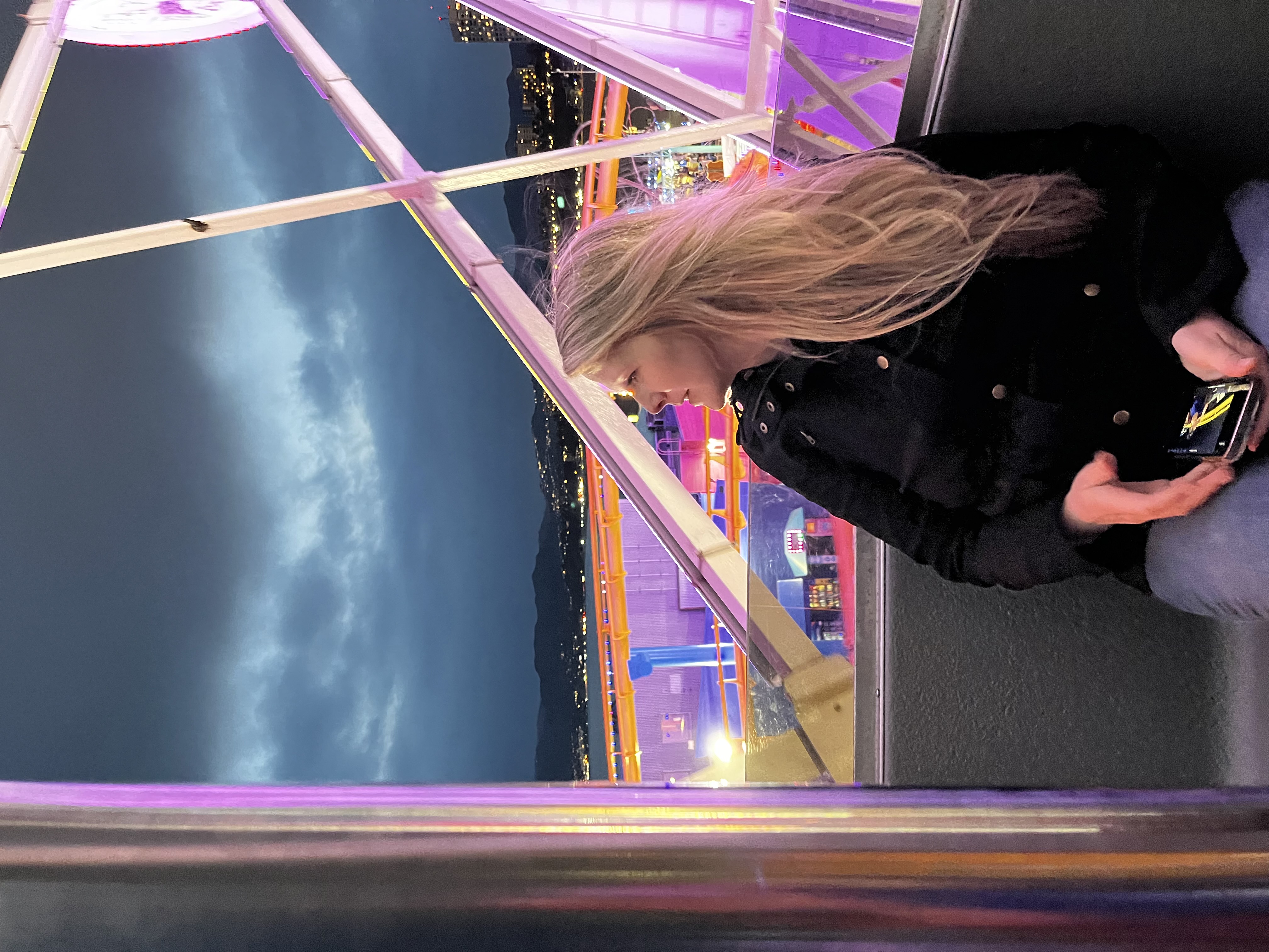Jessica Winchester sitting in front of a brightly colored and lit amusement park